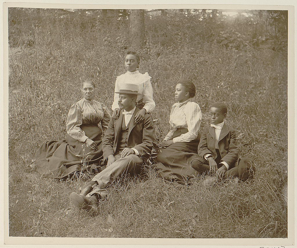 African American family posed for portrait seated on lawn, 1899 or 1900